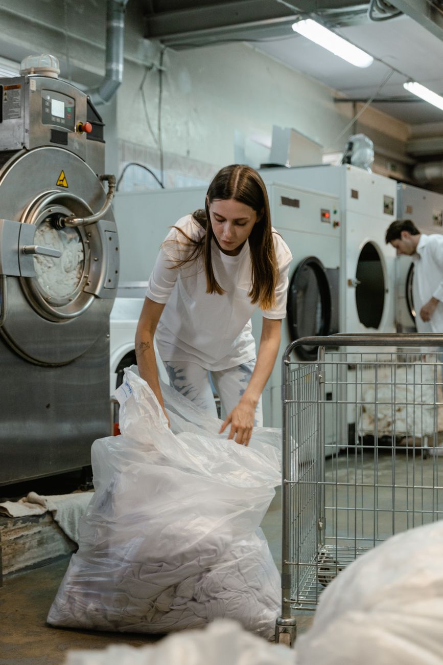 Woman handling laundry in a commercial washing facility, focusing on tasks and efficiency.