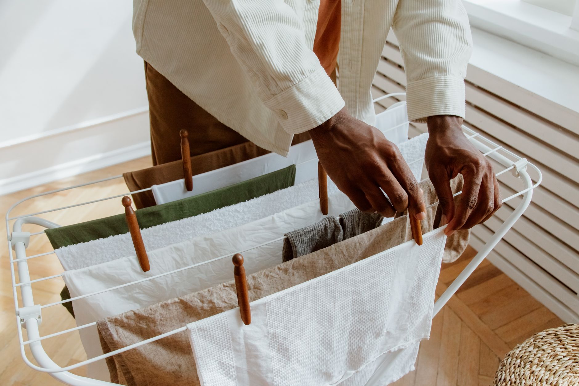 A close-up of a person hanging laundry on an indoor drying rack, highlighting domestic life.