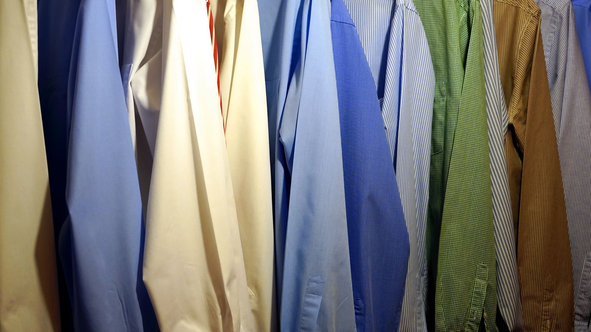 A colorful collection of dress shirts hanging indoors showcasing various styles and patterns.